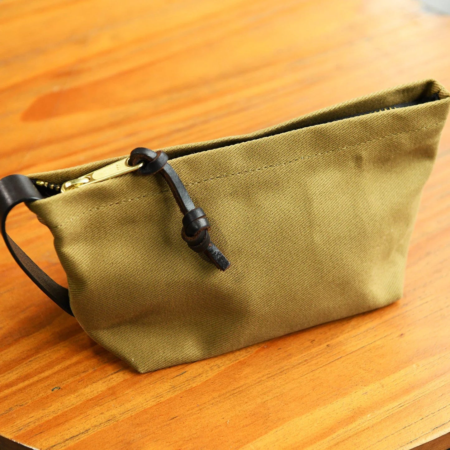 Khaki waxed canvas travel pouch with leather wrist loop