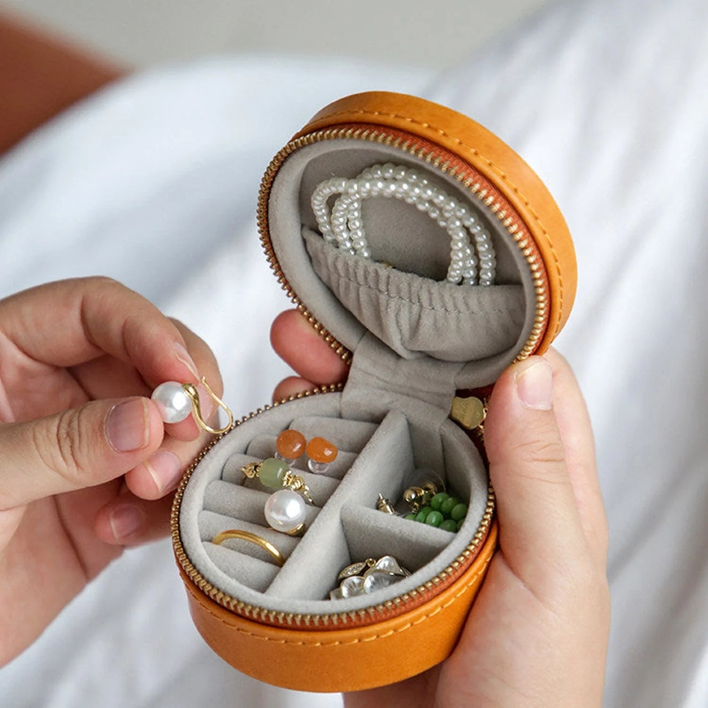 Interior organizer detail of round leather travel jewelry case with necklace pocket and divided compartments