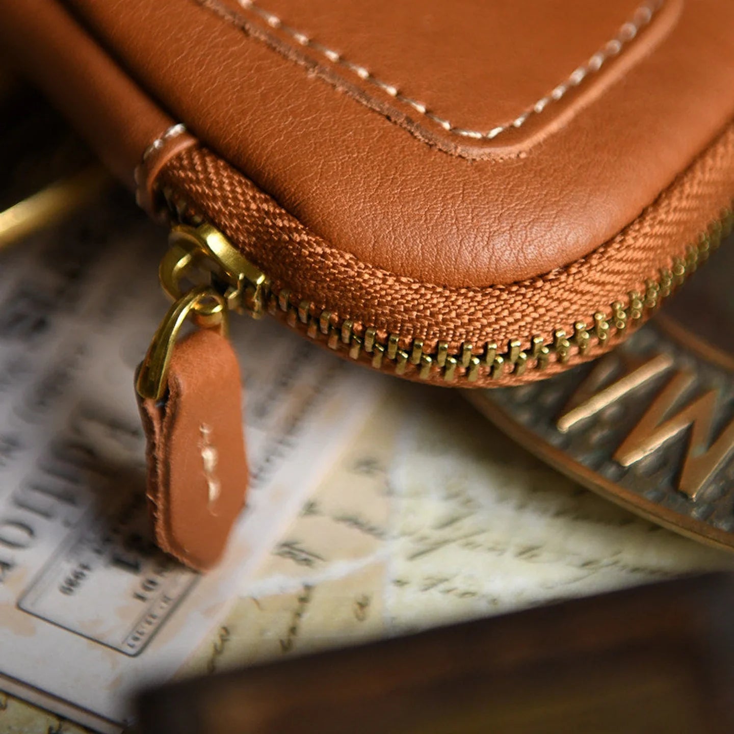 Close-up of contrast stitching and brass-tone zipper on a leather key case