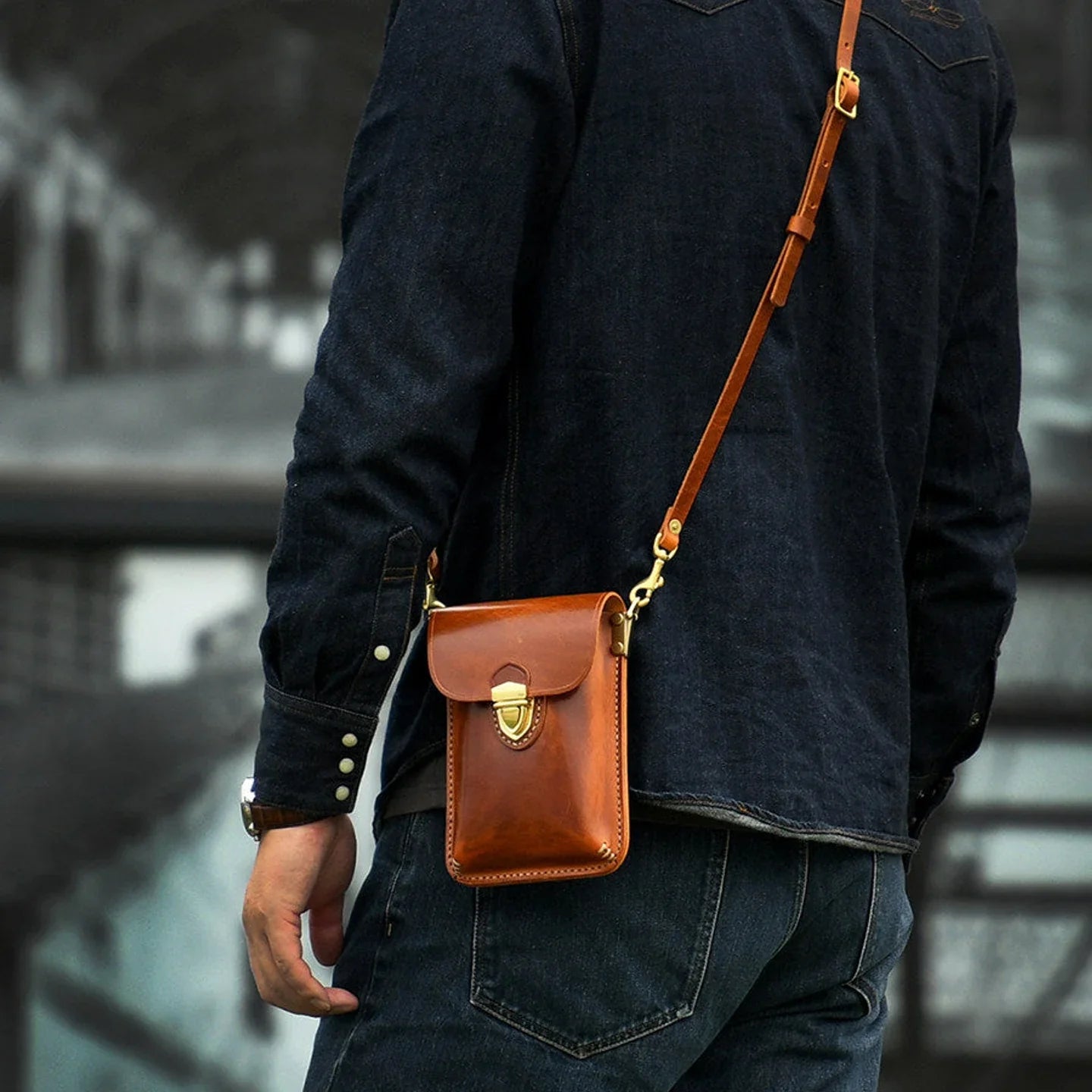 Compact leather phone bag worn crossbody across the back