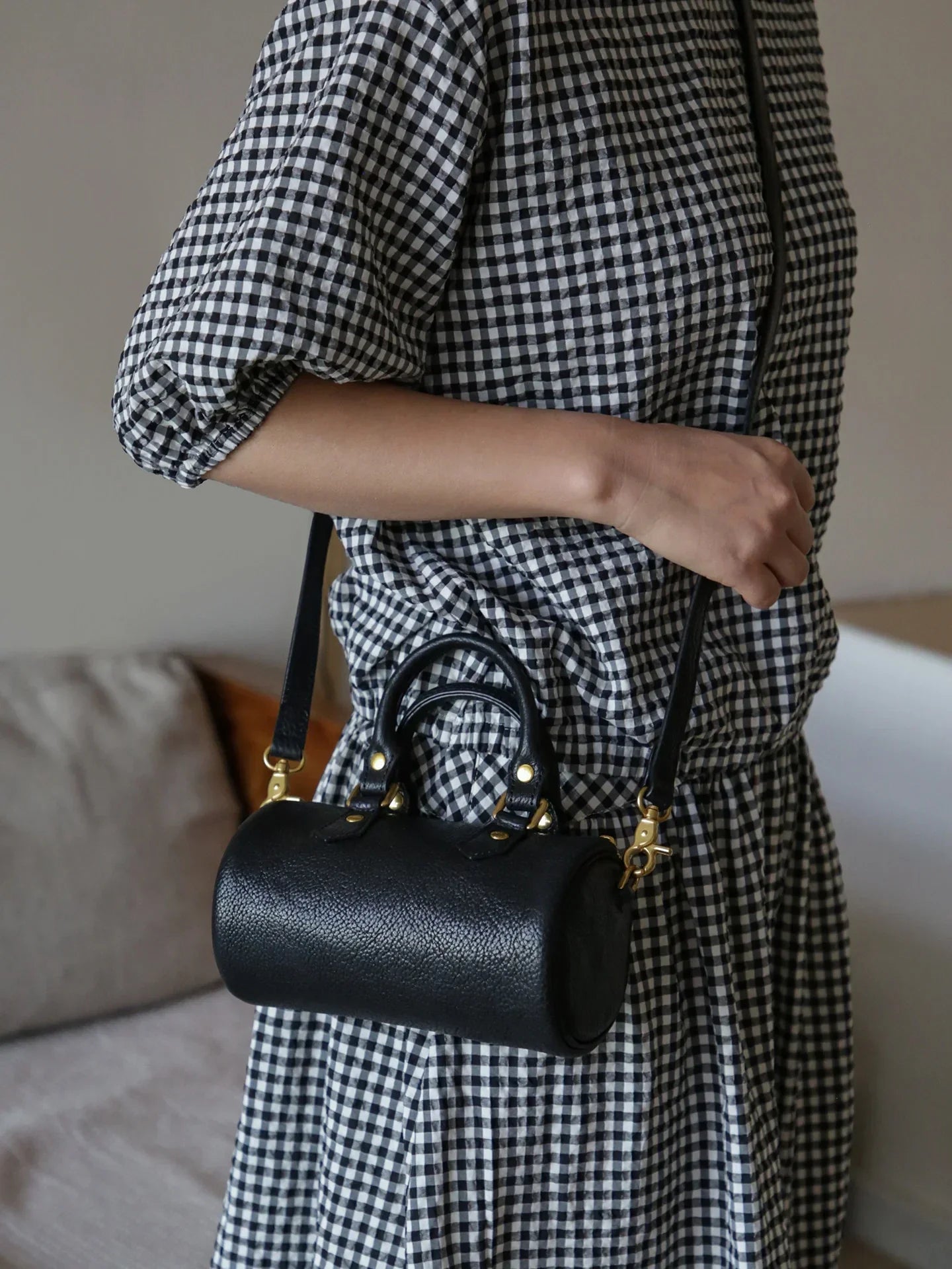 Black top-grain leather mini barrel bag worn crossbody