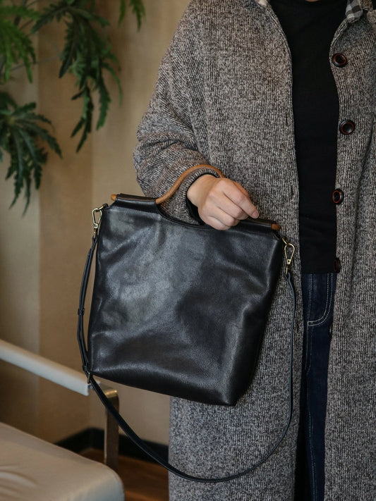Black vegetable-tanned leather convertible tote bag carried by hand