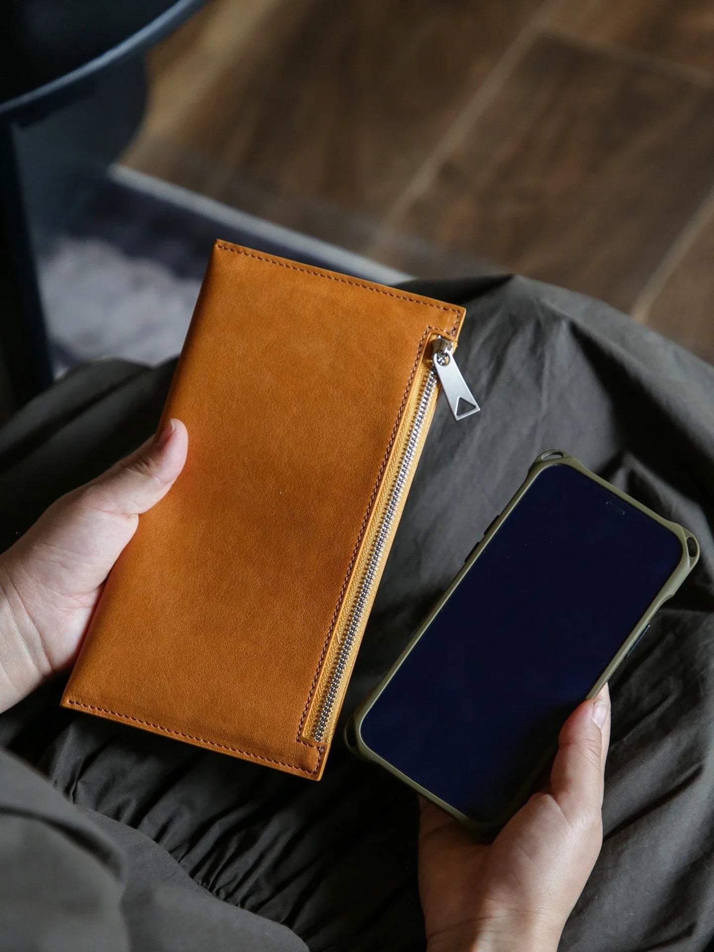 Caramel leather long wallet shown beside a smartphone for scale