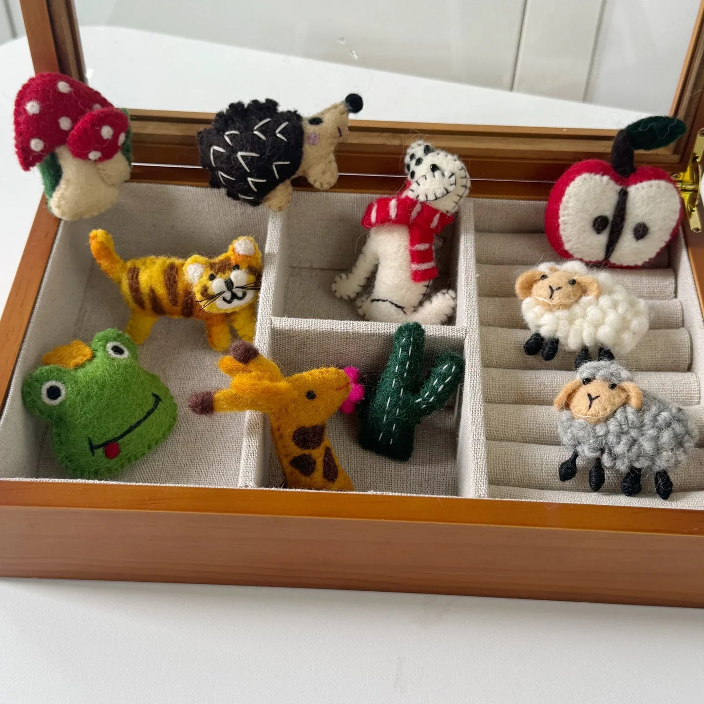 Colorful handmade wool felt animal brooches arranged in a wooden display tray