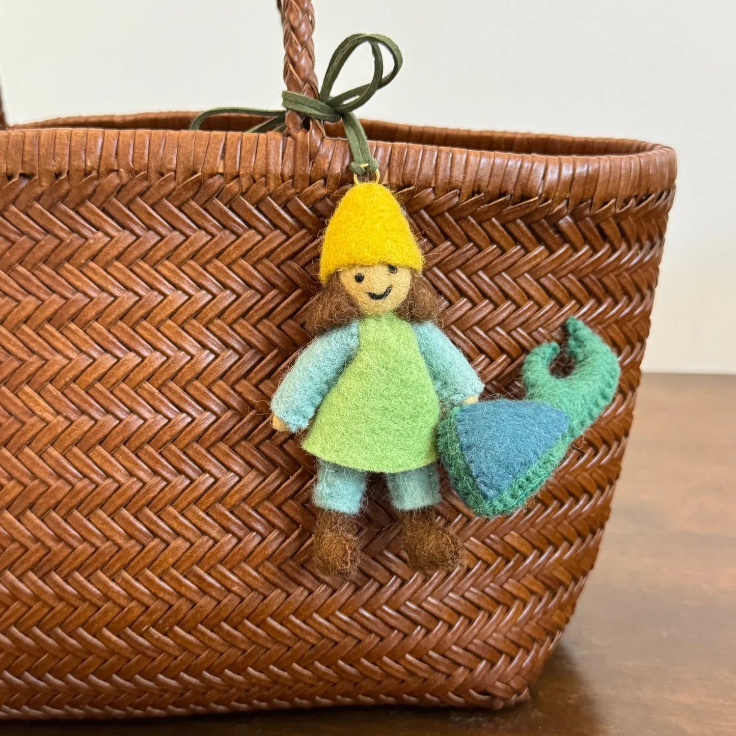 Front view of the wool felt girl and beetle bag charm with green leather cord