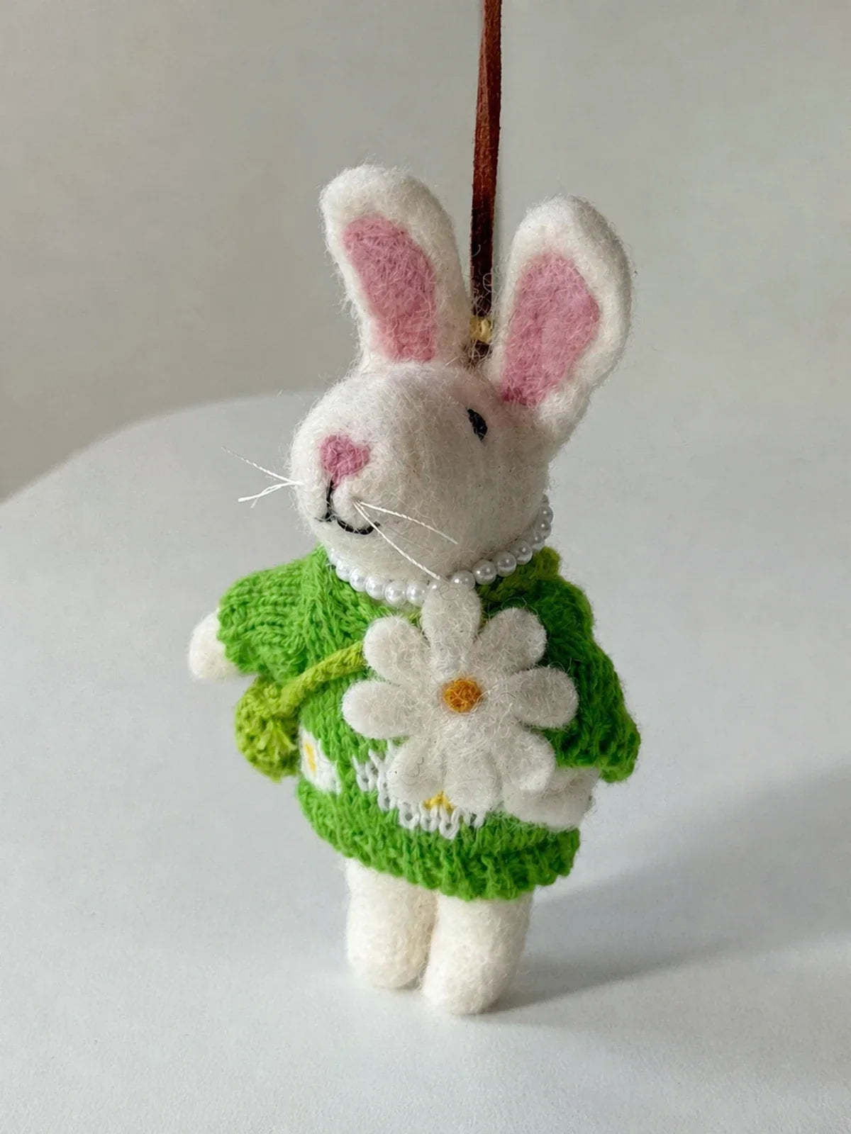 Front and side view of a handmade wool felt rabbit charm with knitted dress