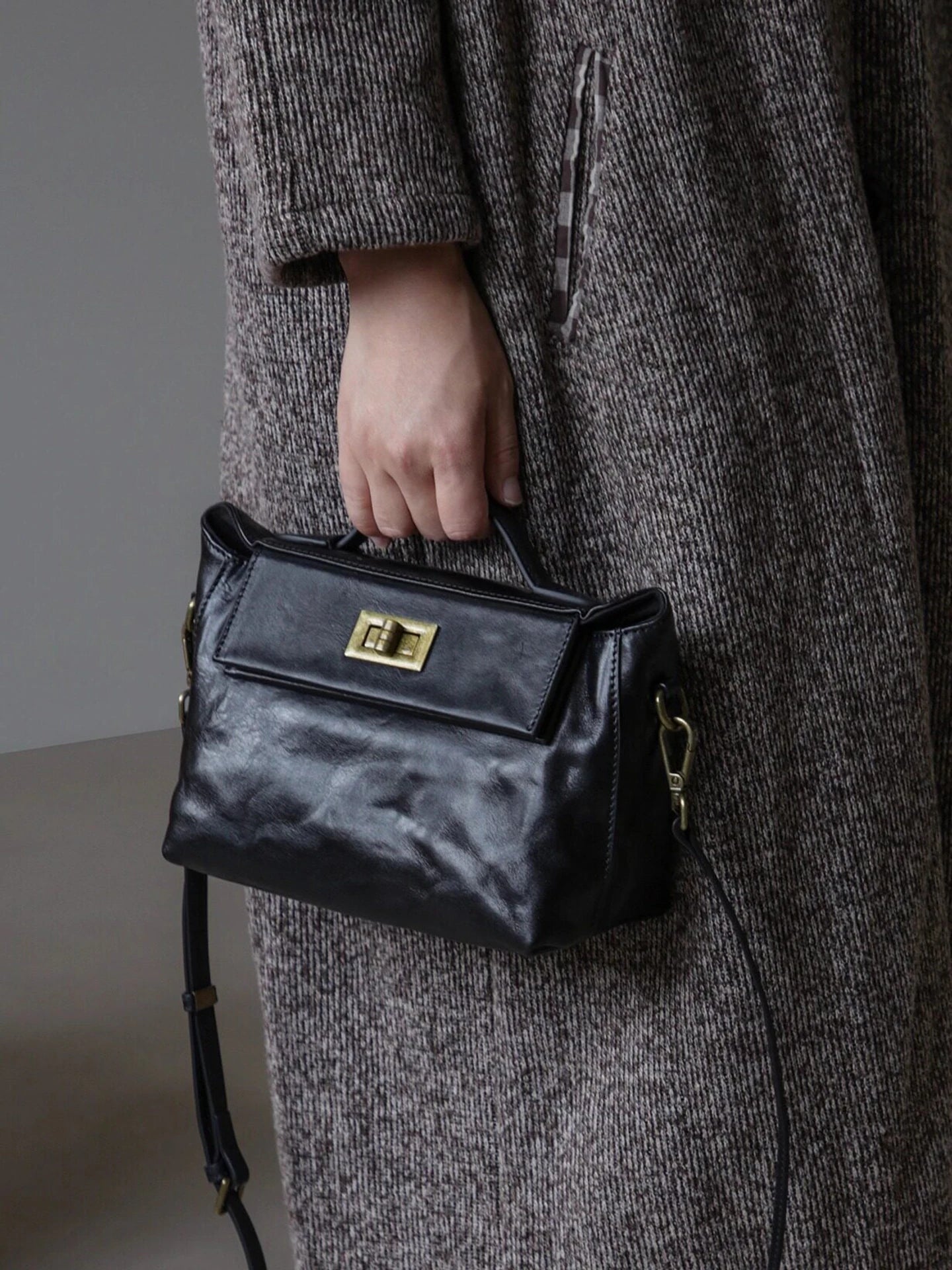 Black vegetable-tanned leather satchel carried by the top handle