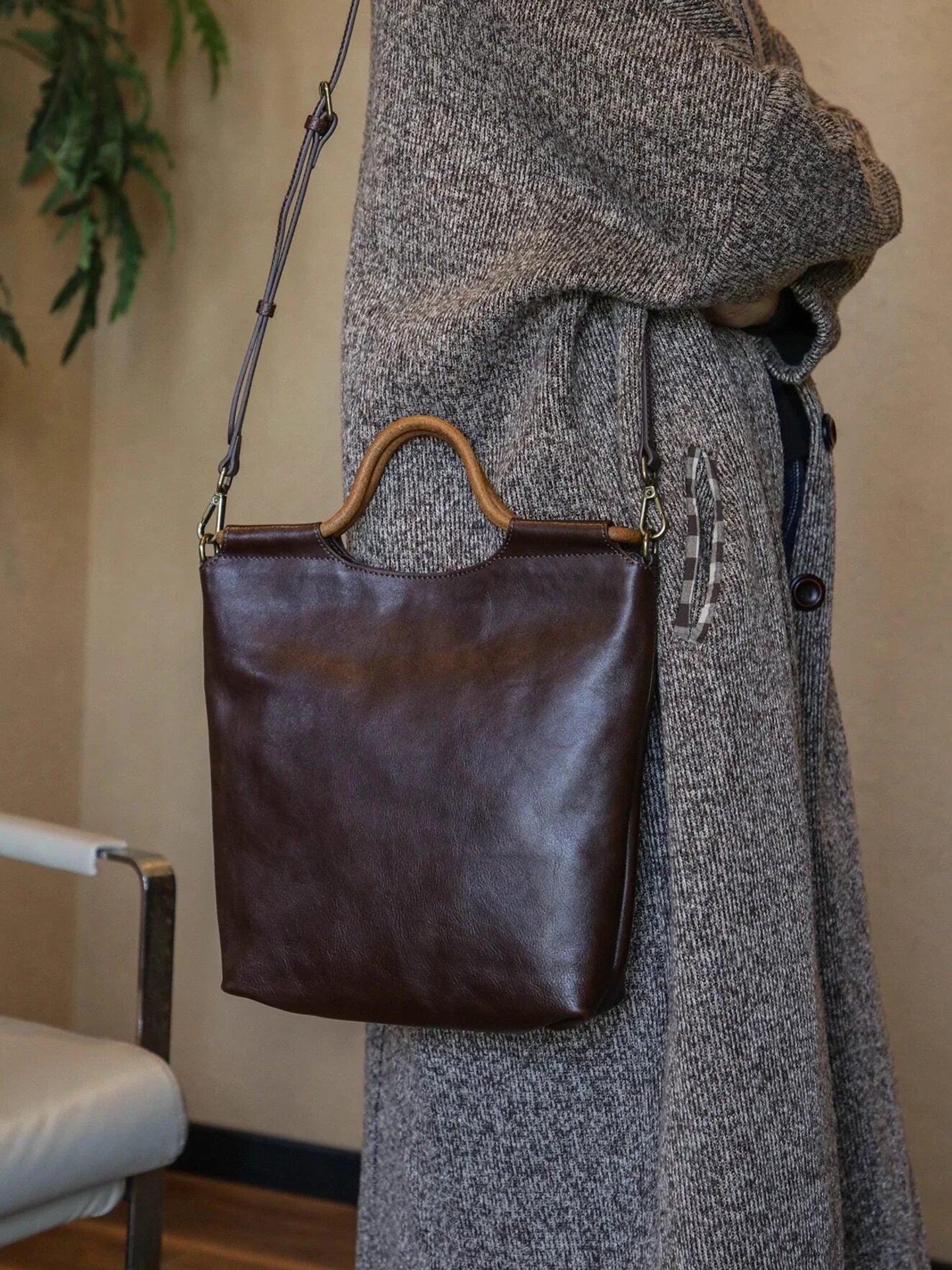Ebony brown leather tote bag worn with the adjustable shoulder strap
