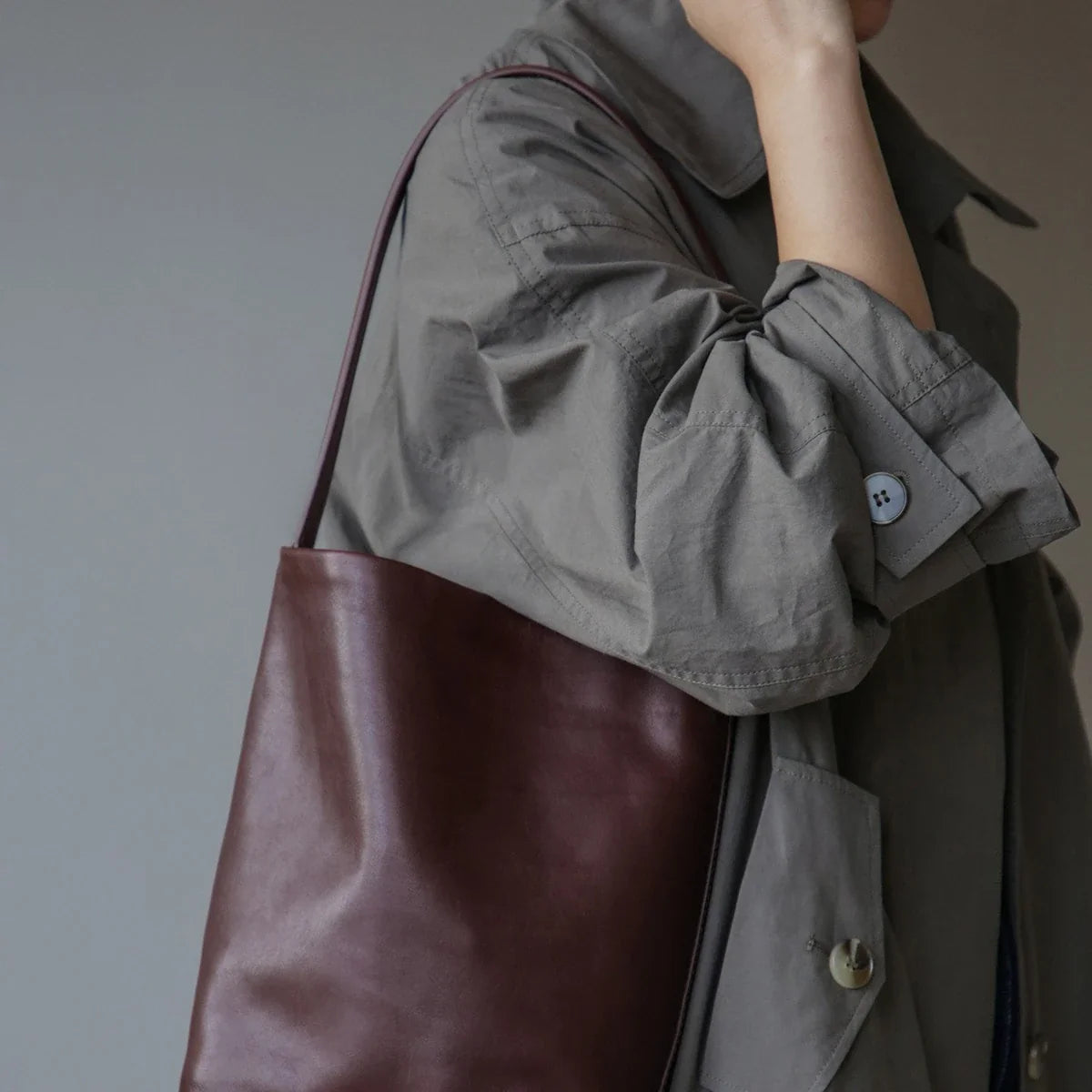 Women's ebony coffee leather bucket bag in an everyday shoulder styling view