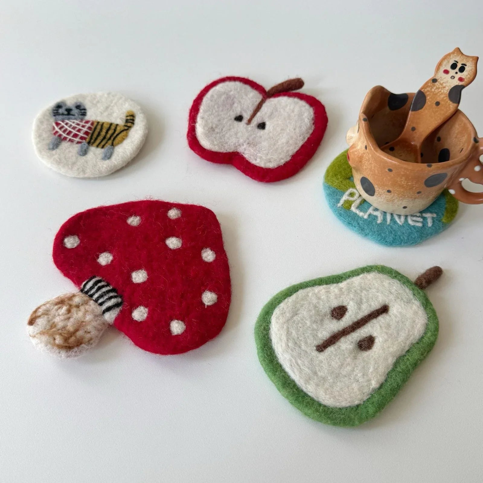 Red mushroom and apple slice wool felt coasters on a tabletop