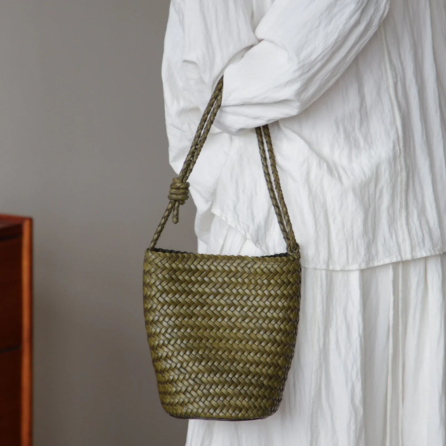 Olive green woven leather bucket bag worn on the shoulder