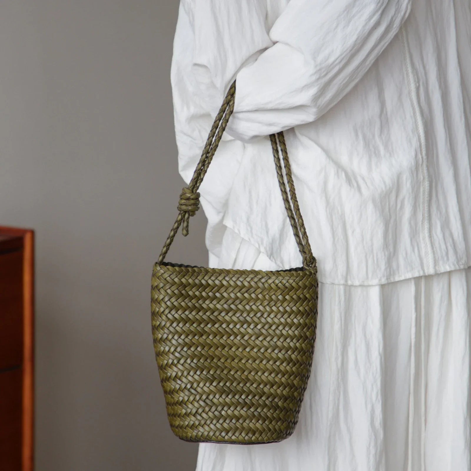 Olive green woven leather bucket bag worn on the shoulder