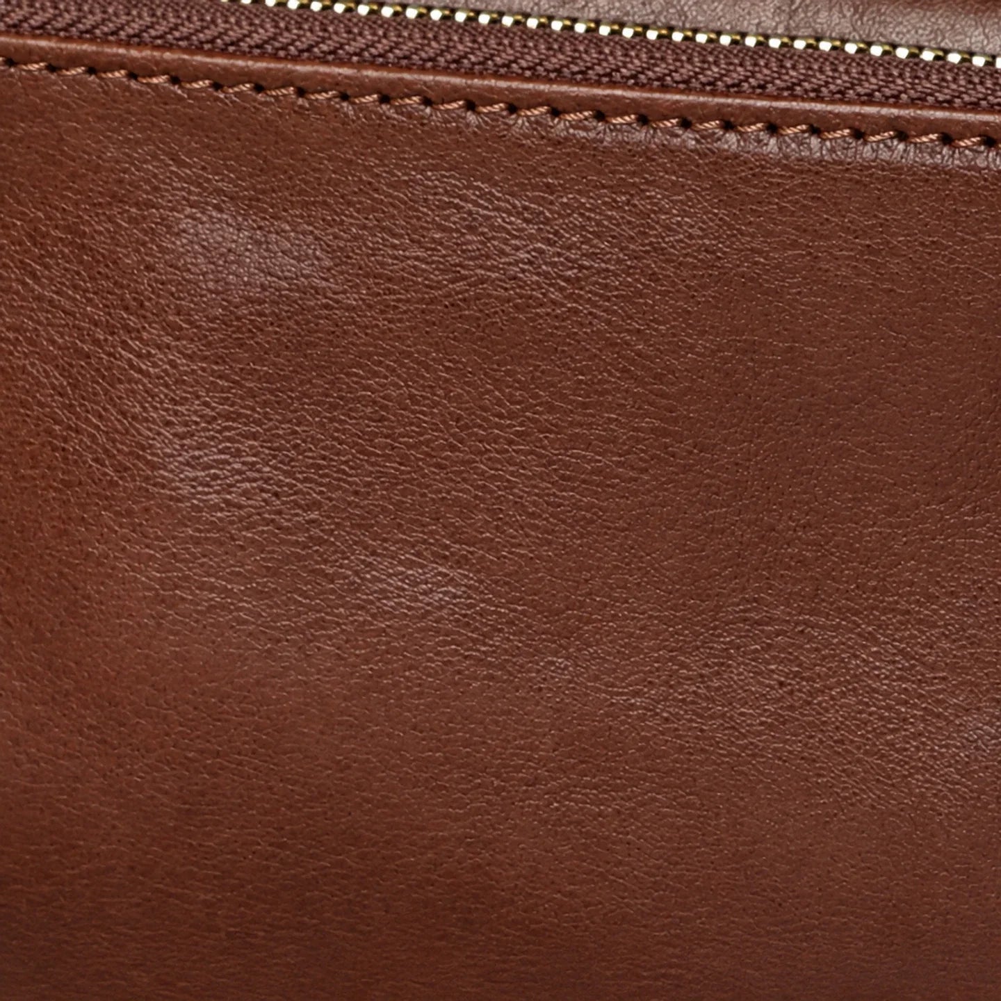 Close-up of brown top-grain leather texture, stitching and zipper