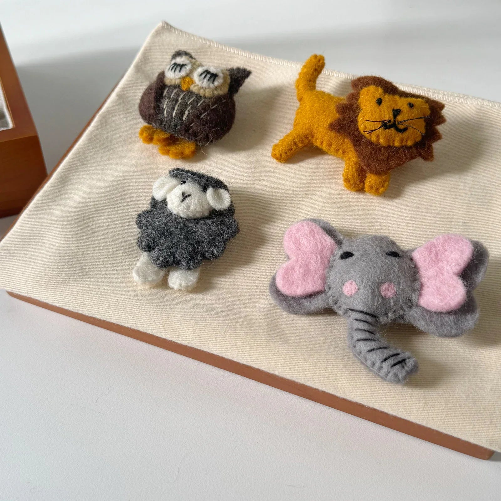 Close-up of handmade wool felt owl lion sheep and elephant brooches