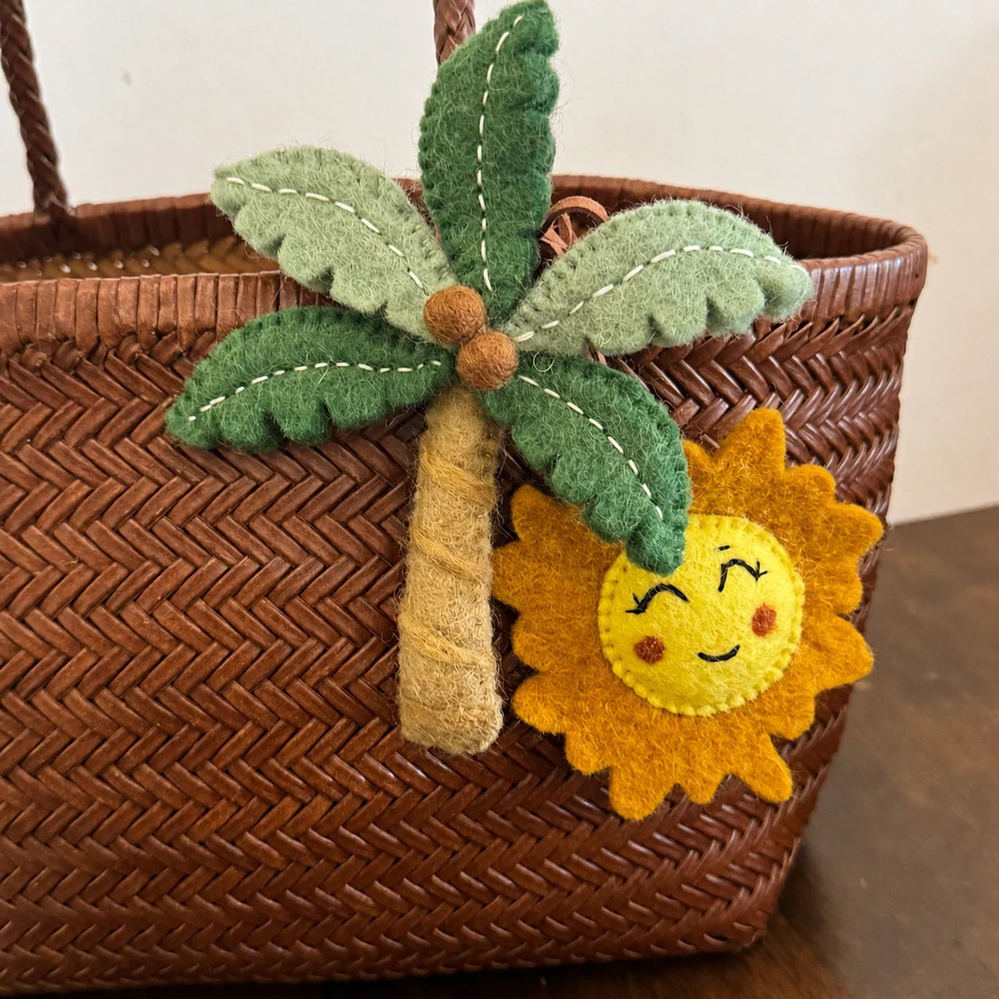 Wool felt palm tree and sun charm with visible hand stitching detail