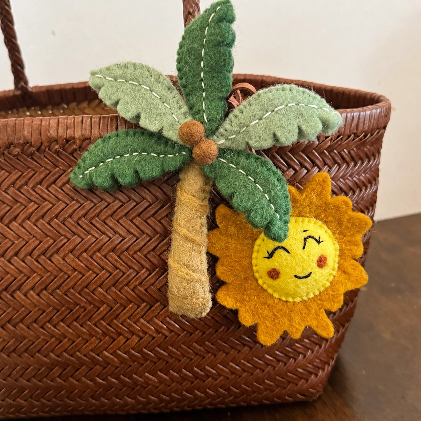 Wool felt palm tree and sun charm with visible hand stitching detail