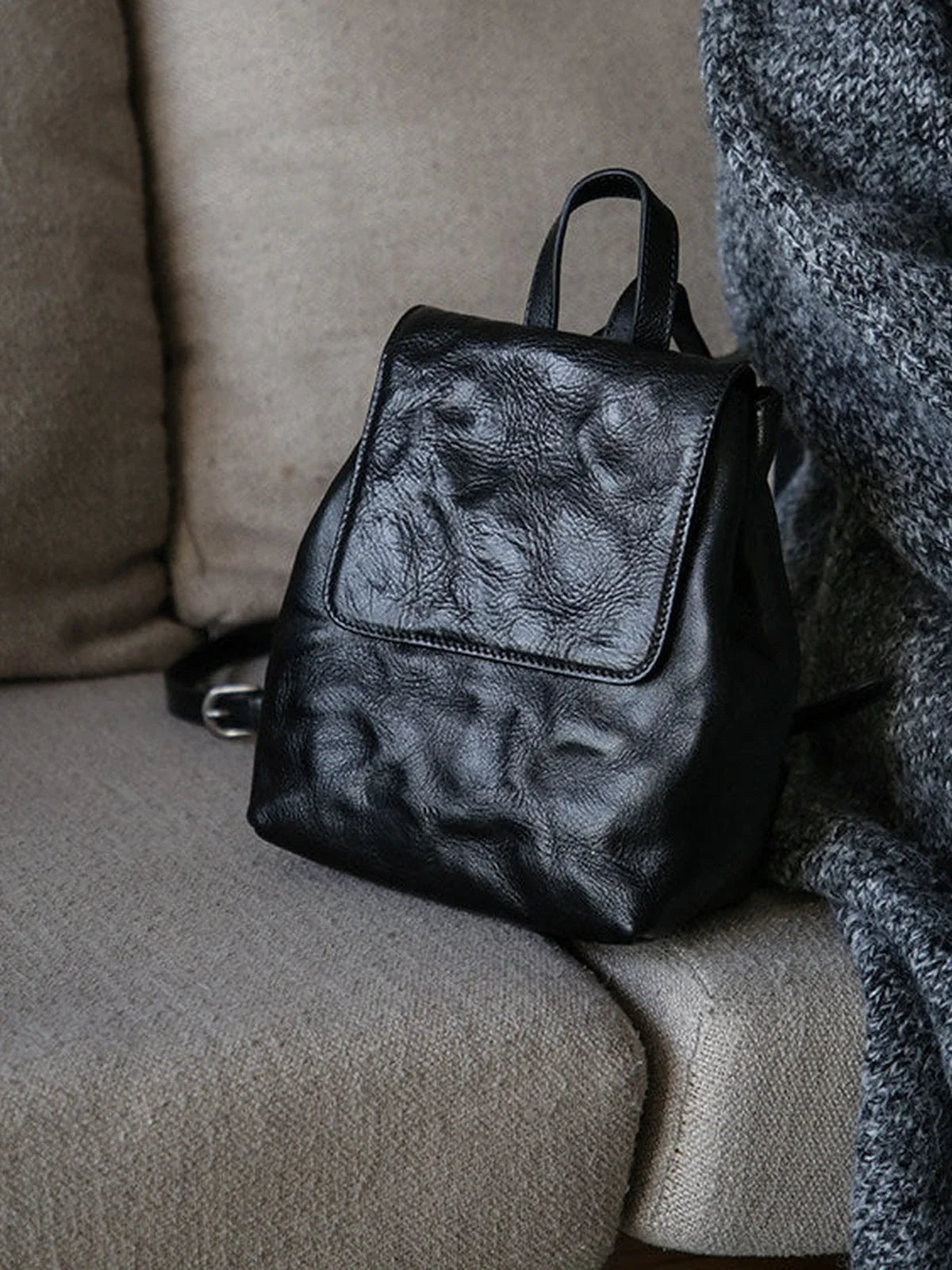 Black cowhide mini backpack full view with top handle and flap