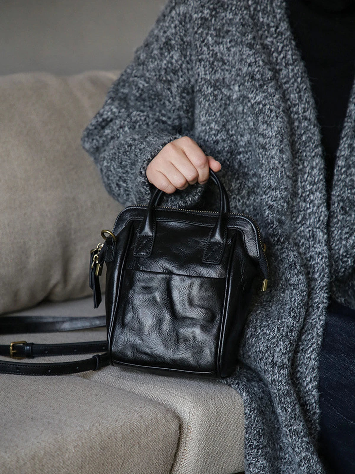 Black leather mini backpack shown from the front with top handles