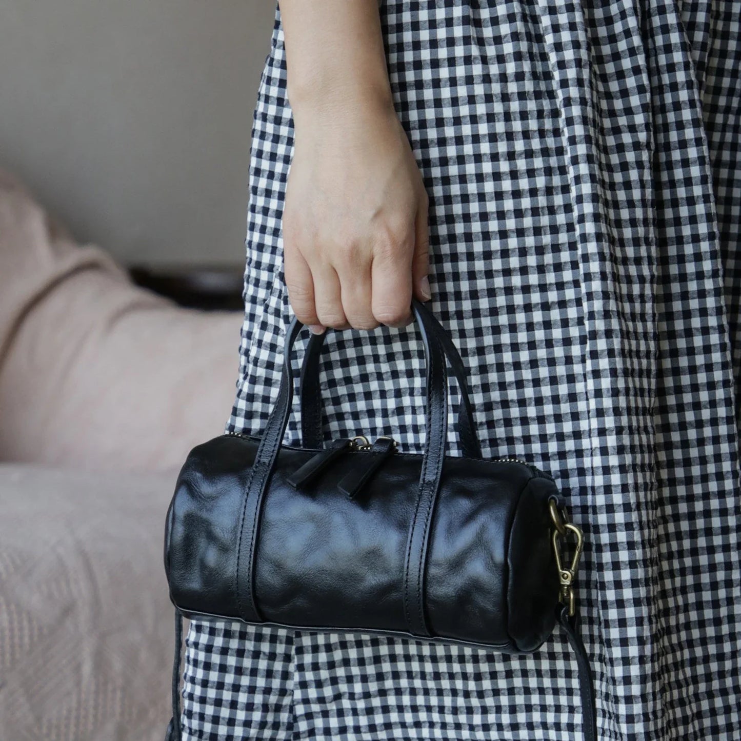 Black vegetable-tanned leather mini barrel bag carried by hand