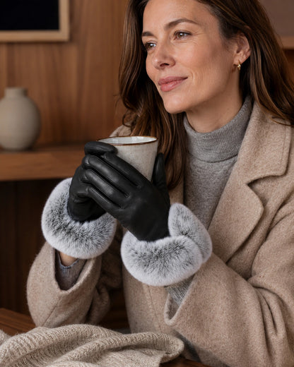 Woman holding coffee in black leather gloves with silver gray fur cuffs