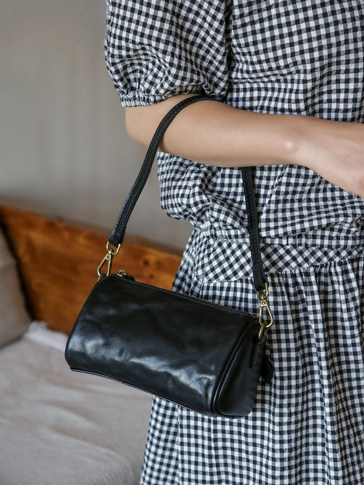 Black leather barrel bag showing natural grain and shoulder strap
