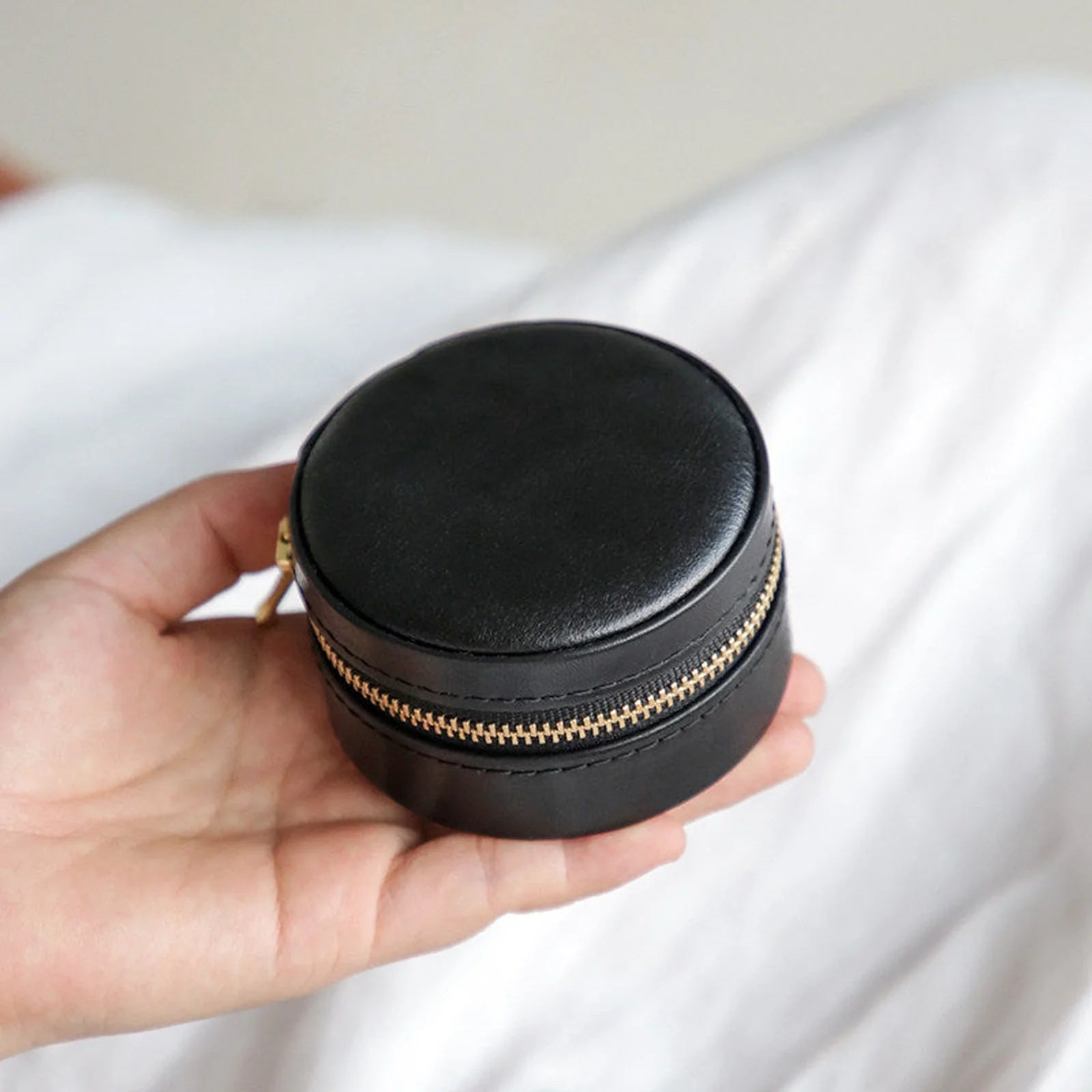Black round vegetable-tanned leather travel jewelry case with zipper closure