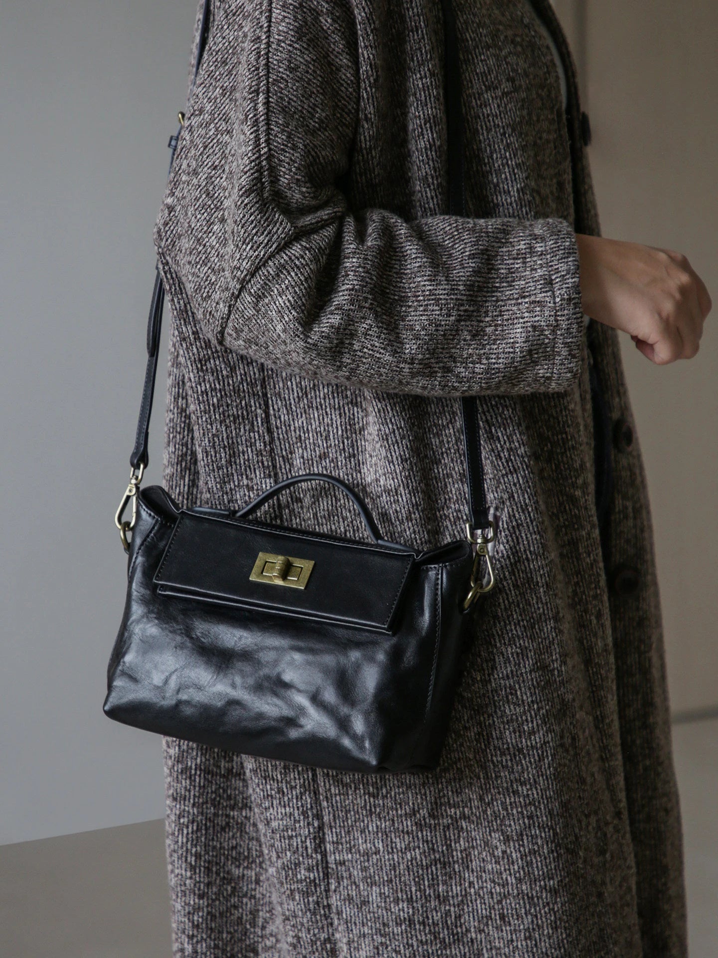 Black leather satchel worn over the shoulder with antique gold-tone hardware