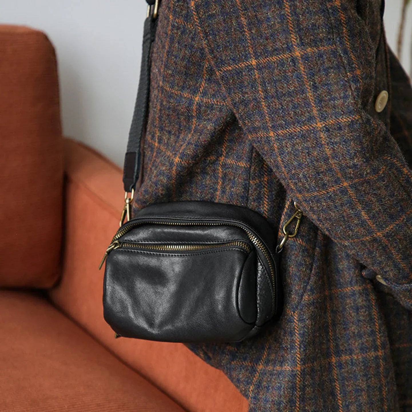 Women's black leather shoulder bag worn crossbody in an everyday interior