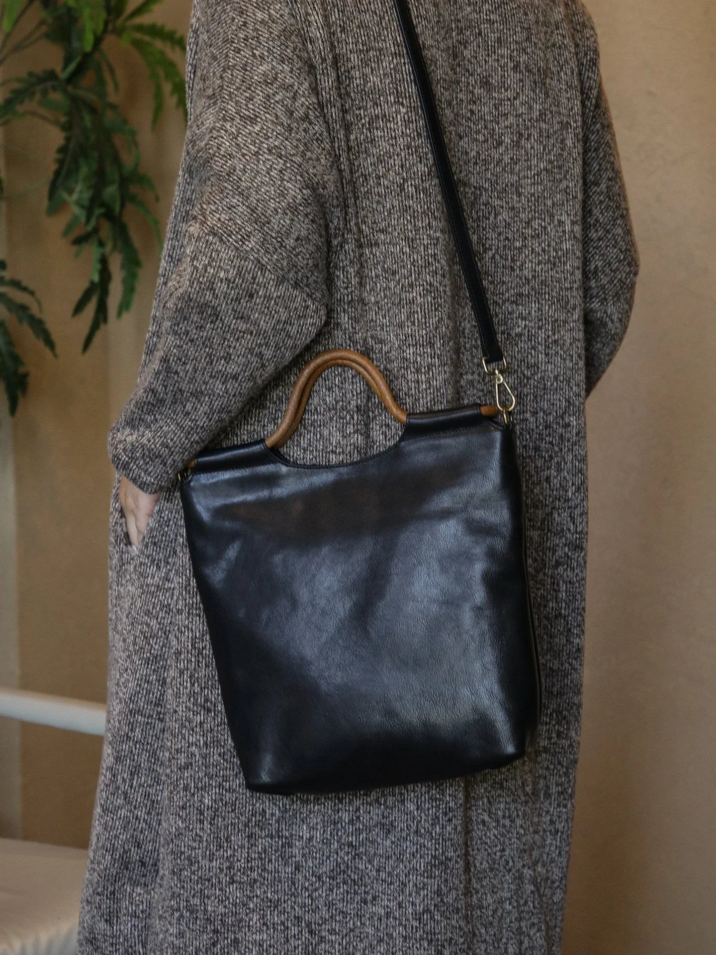 Black leather tote bag worn with the adjustable shoulder strap