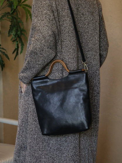 Black leather tote bag worn with the adjustable shoulder strap