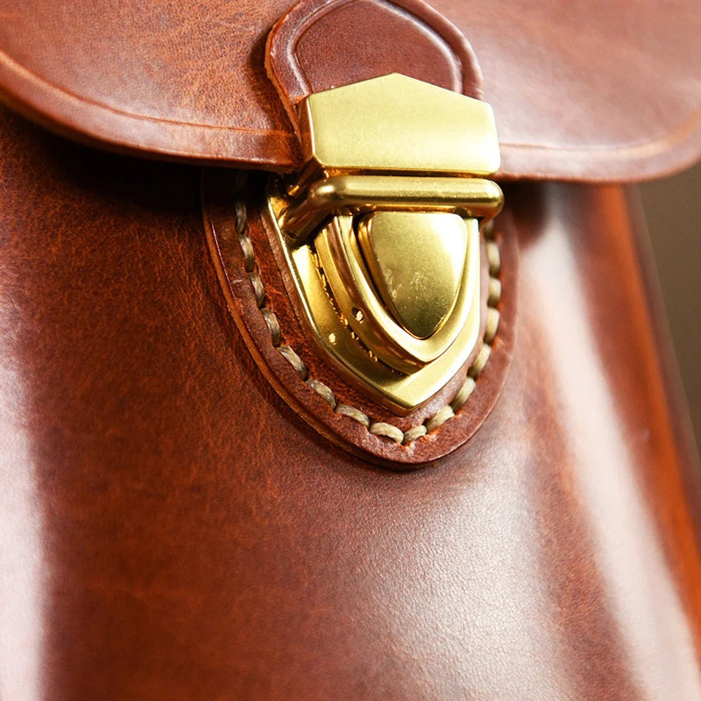 Brass flap clasp and hand-stitching detail on the leather phone bag