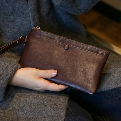 Coffee brown leather long wallet held against a grey knit