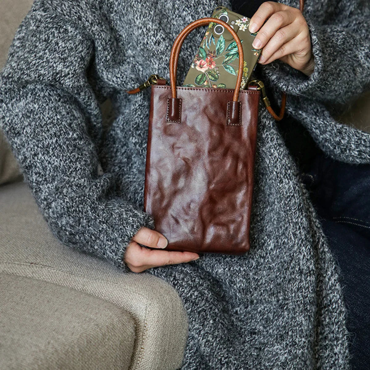 Coffee brown leather mini tote bag shown holding a smartphone