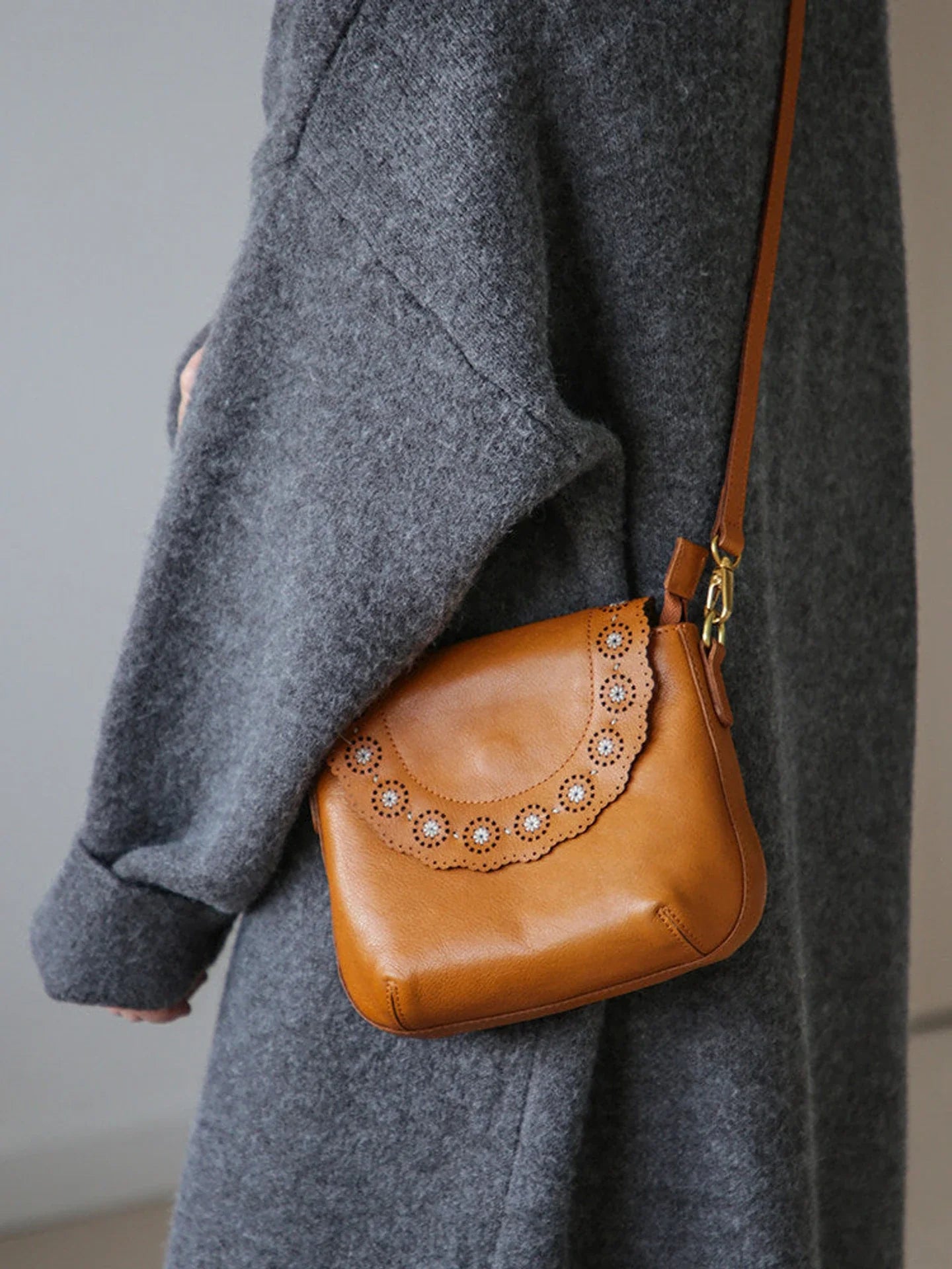 Cognac brown leather crossbody bag showing its side profile and strap