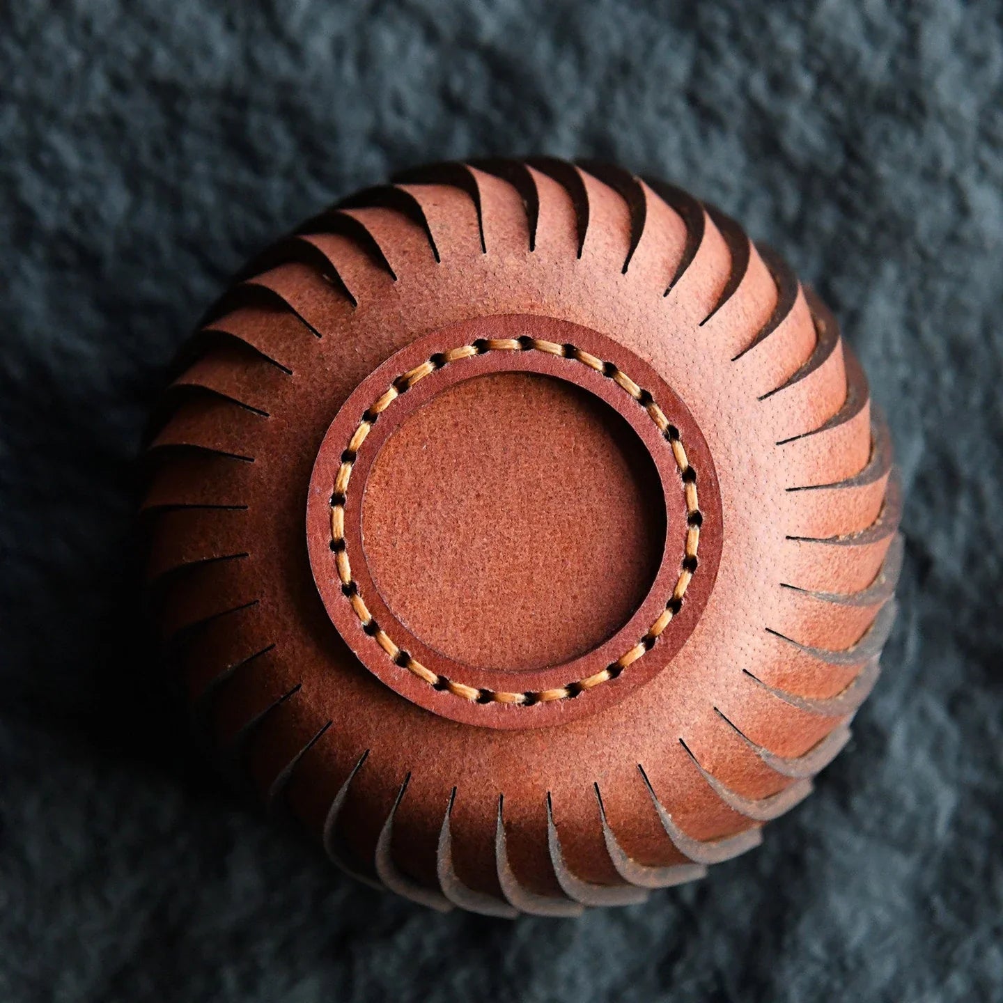 Cowhide storage bowl base with decorative stitching and leather construction detail