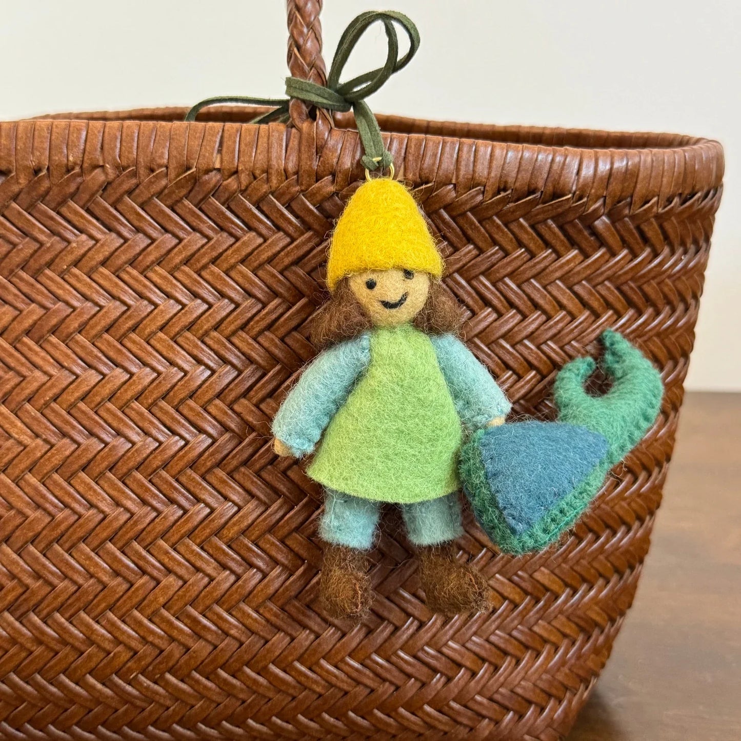 Close detail of the girl and beetle wool felt charm with leather cord attachment