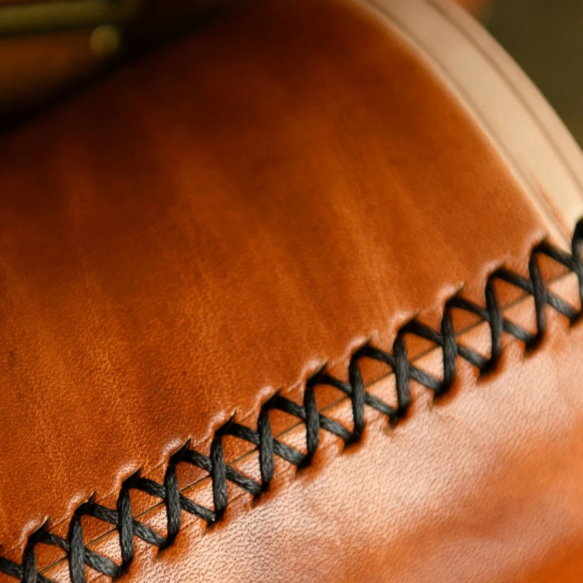 Hand-laced cross-stitch seam detail on brown leather