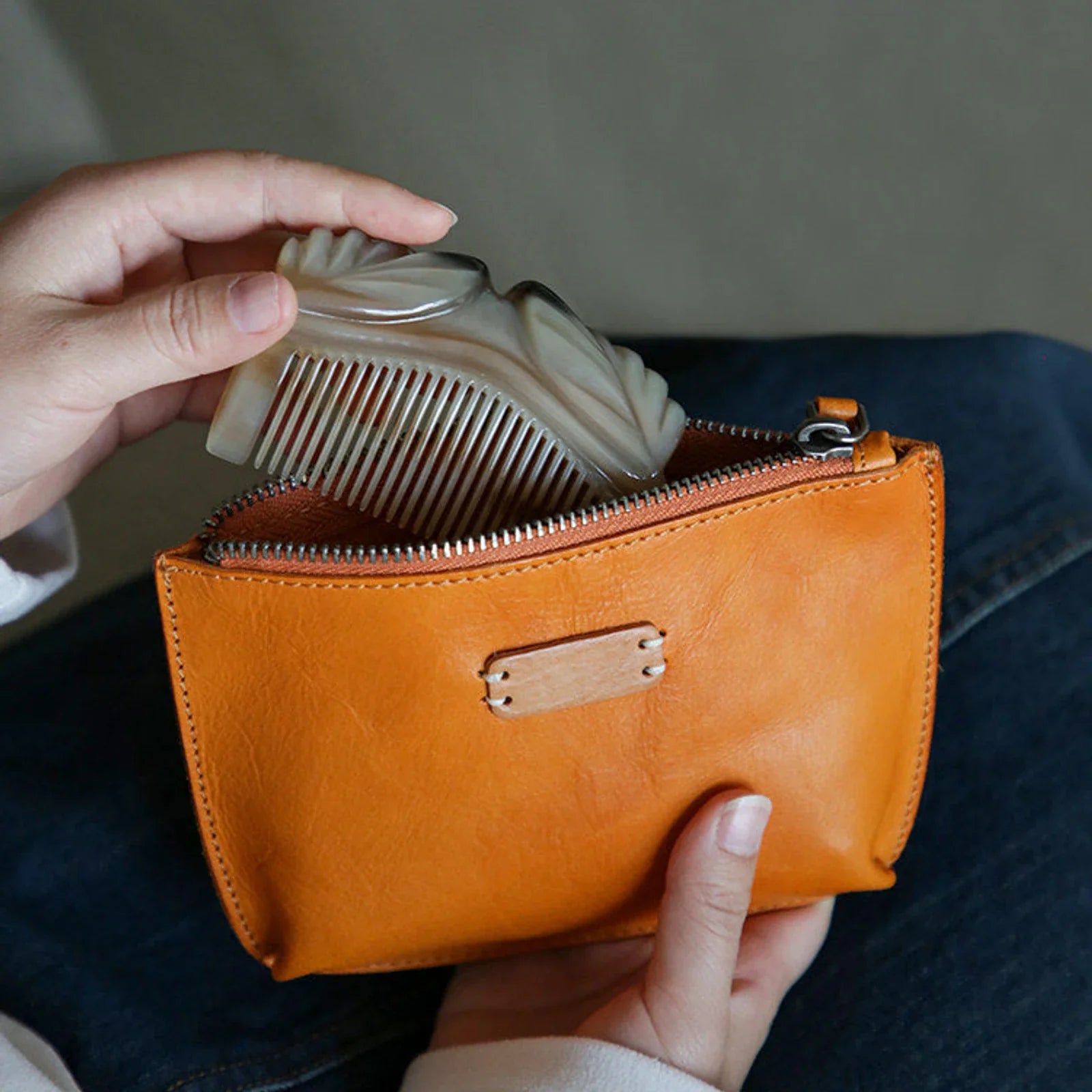 Sunset yellow leather cosmetic pouch holding a compact and other small essentials