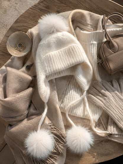 White knit earflap pom-pom hat styled with neutral winter layers