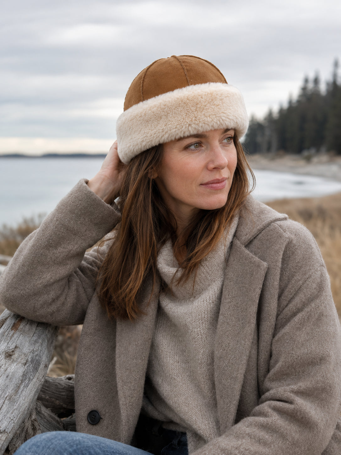 Woman wearing a camel and ivory wool shearling winter hat by the coast