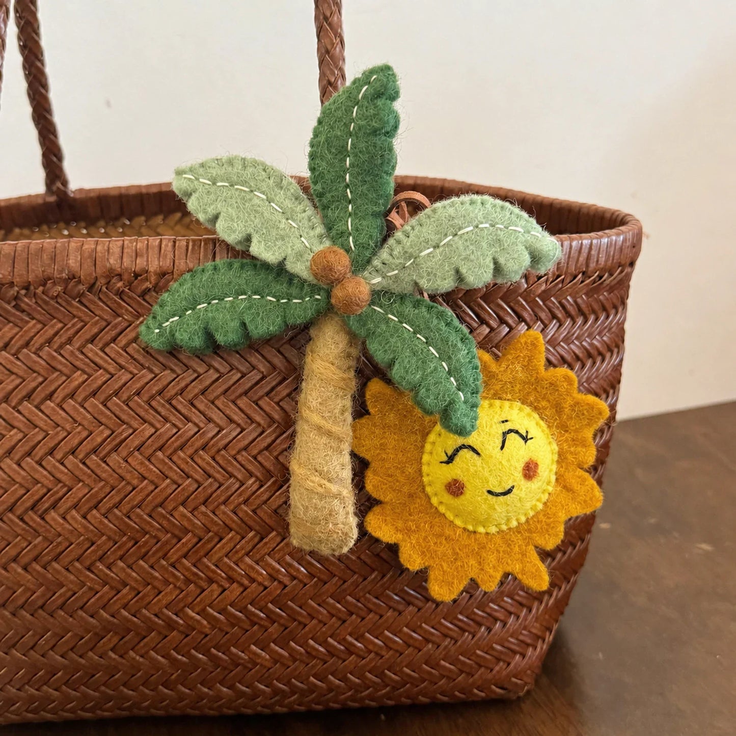 Angled view of wool felt palm tree and smiling sun bag charms