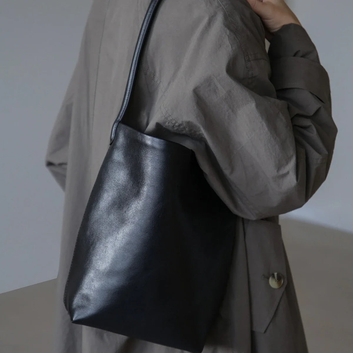 Women's black drawstring bucket bag in a side shoulder-carry view