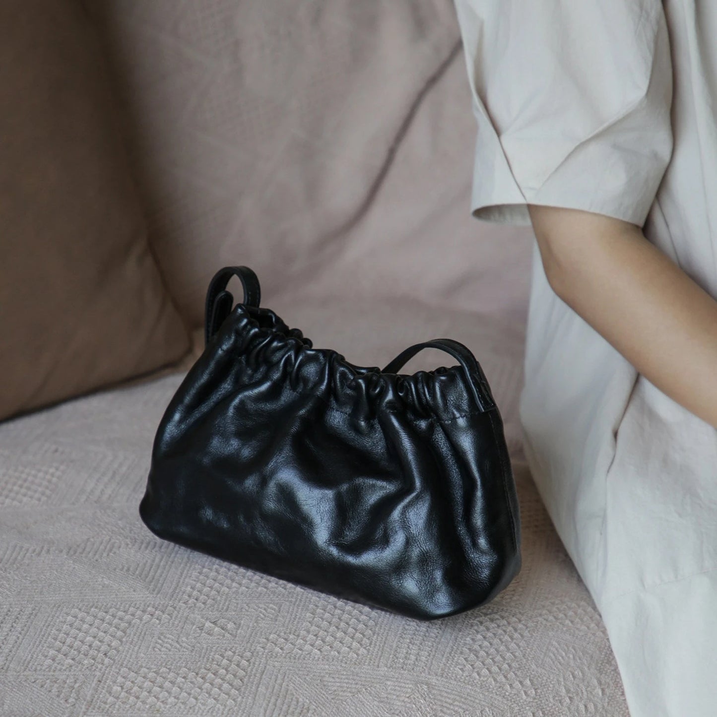 Black gathered leather shoulder bag in a relaxed lifestyle setting