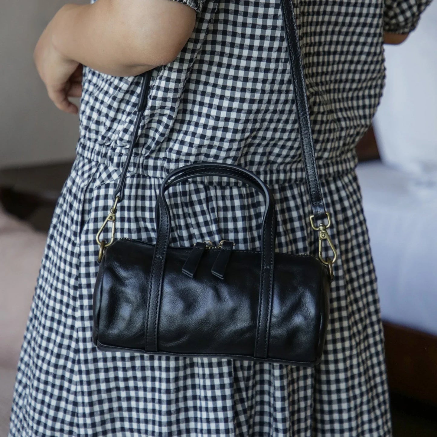 Black vegetable-tanned leather mini barrel bag worn crossbody