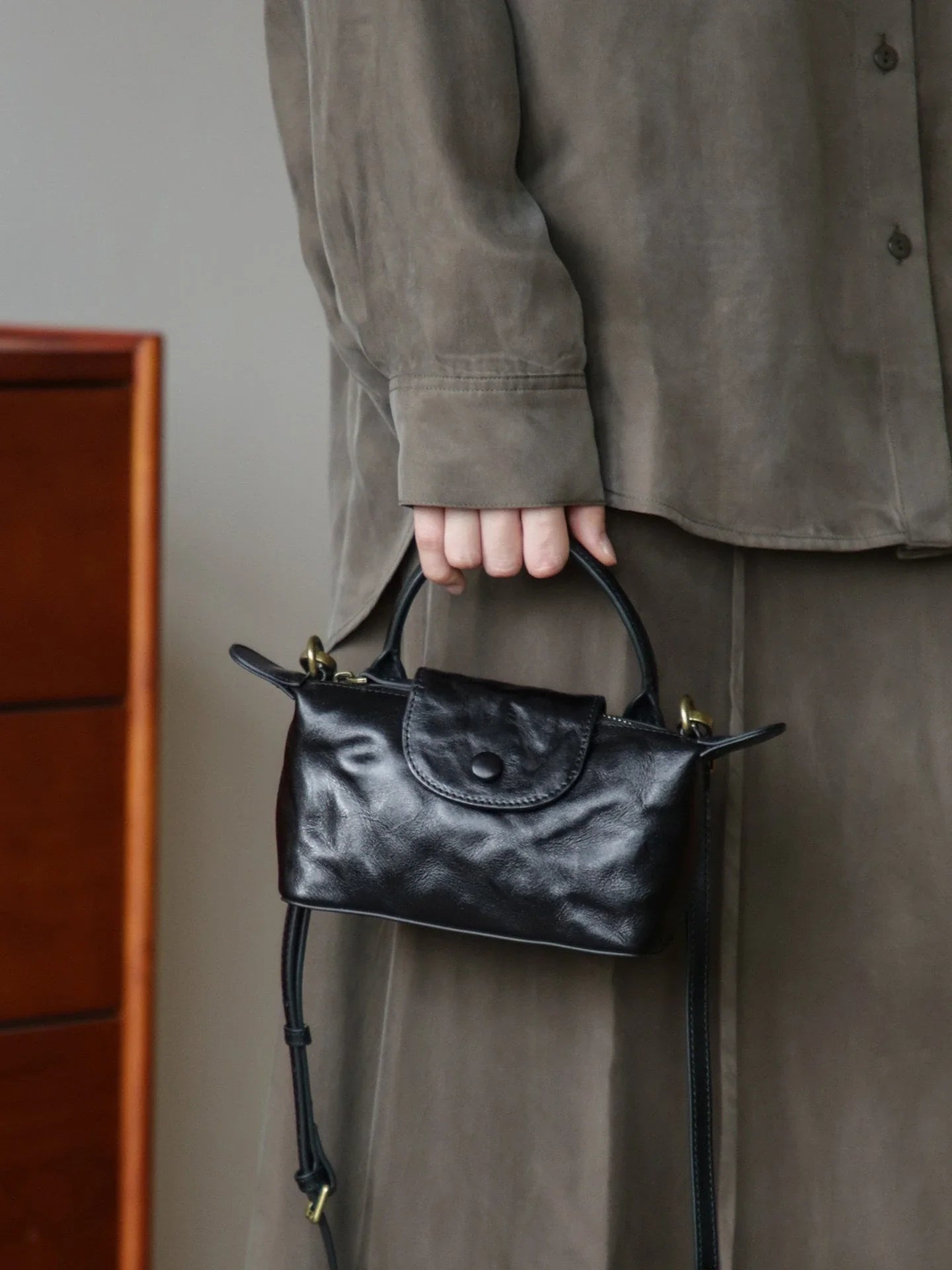 Black vegetable-tanned leather mini bag carried by the top handle