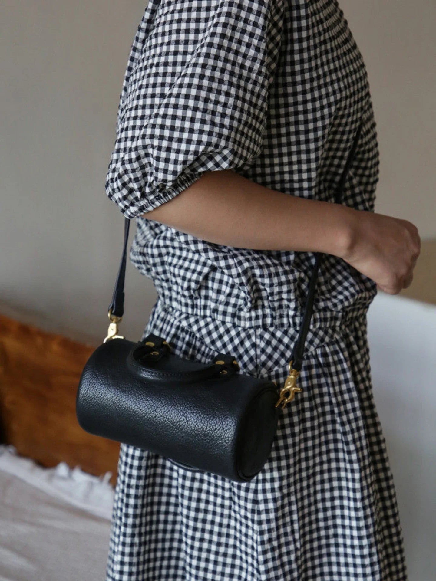 Black leather barrel bag with detachable strap and gold-tone hardware