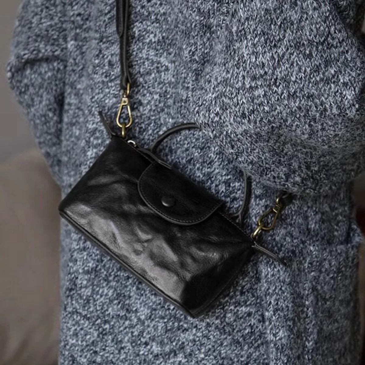 Black vegetable-tanned leather mini crossbody bag worn over the shoulder