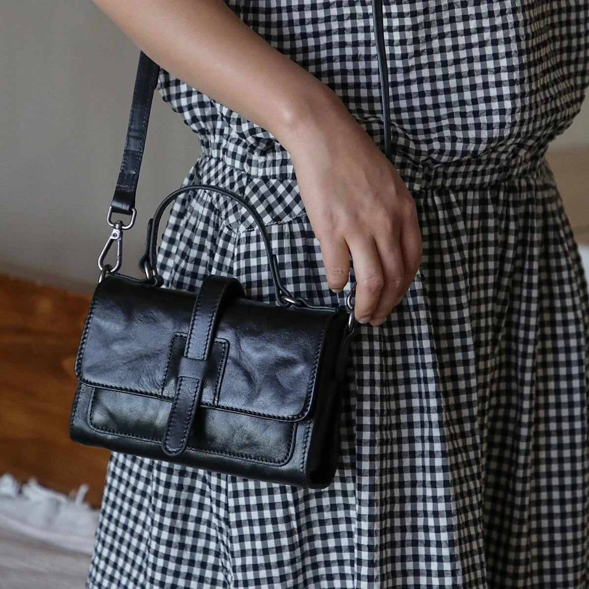 Black top-grain cowhide mini bag carried by the top handle