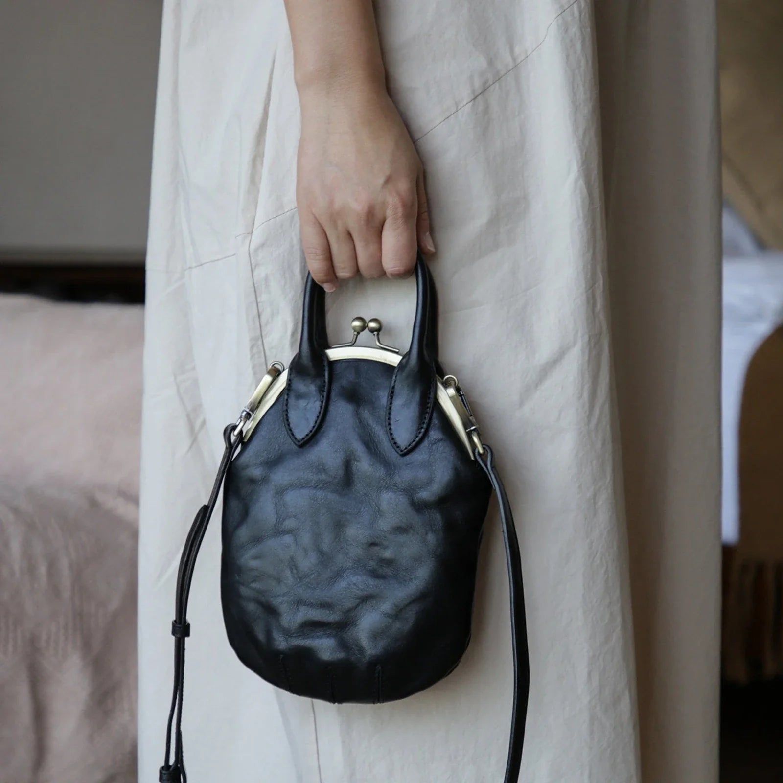 Black vintage leather clasp phone bag carried by the top handles