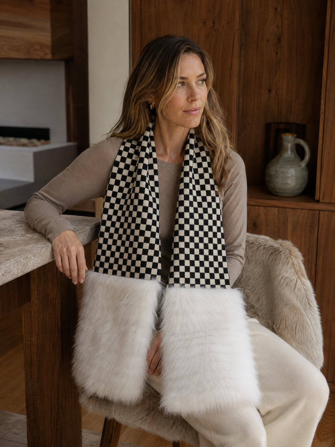 Woman wearing a black-and-white checkerboard fox fur scarf while seated indoors